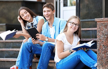 Students reading while sitting on stairs outdoors