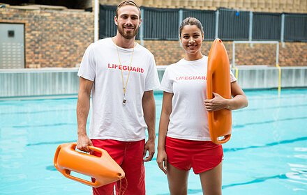 Two lifeguards standing with rescue buoy at poolside